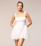 Woman wearing a white lace dress against a plain background