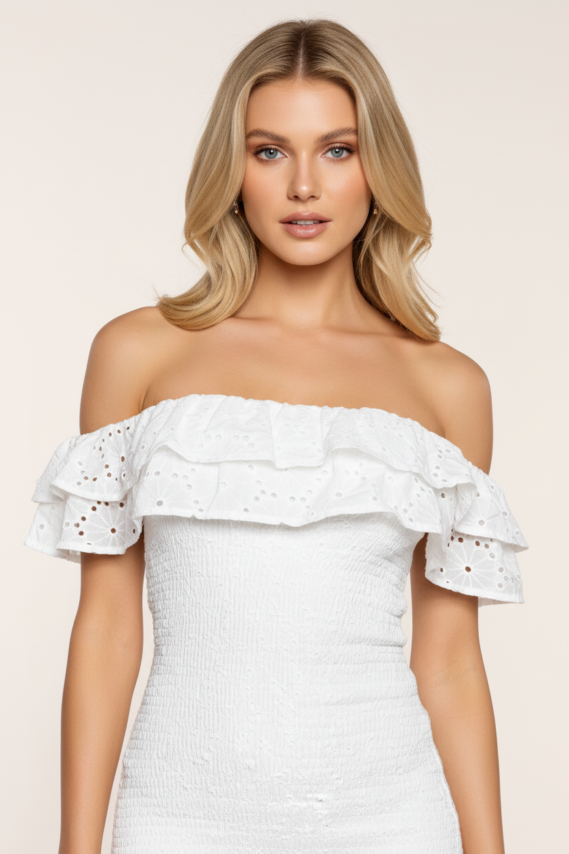 Close-up detail of white eyelet woven fabric with ruffled off-the-shoulder neckline – smocked bodycon mini dress on blonde European model