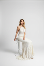 Ivory crochet halter mermaid formal dress seated view – full silhouette on white stool