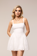 White knit lace skater mini dress close-up bodice view – square neckline with layered gold necklace and gold hoop earrings on blonde European model