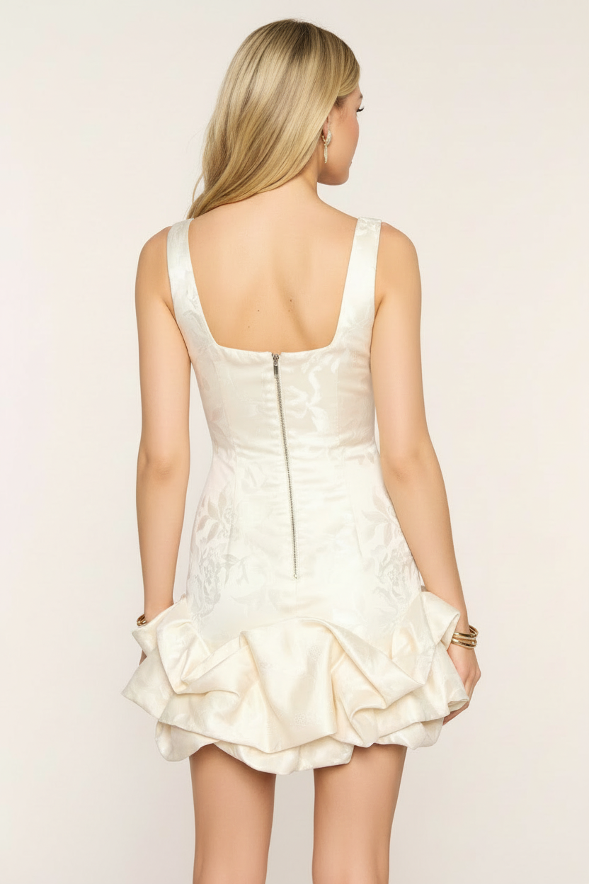 Ivory floral jacquard bodycon mini dress straight back view – back zipper closure structured ruffle hem with gold bracelets on blonde European model